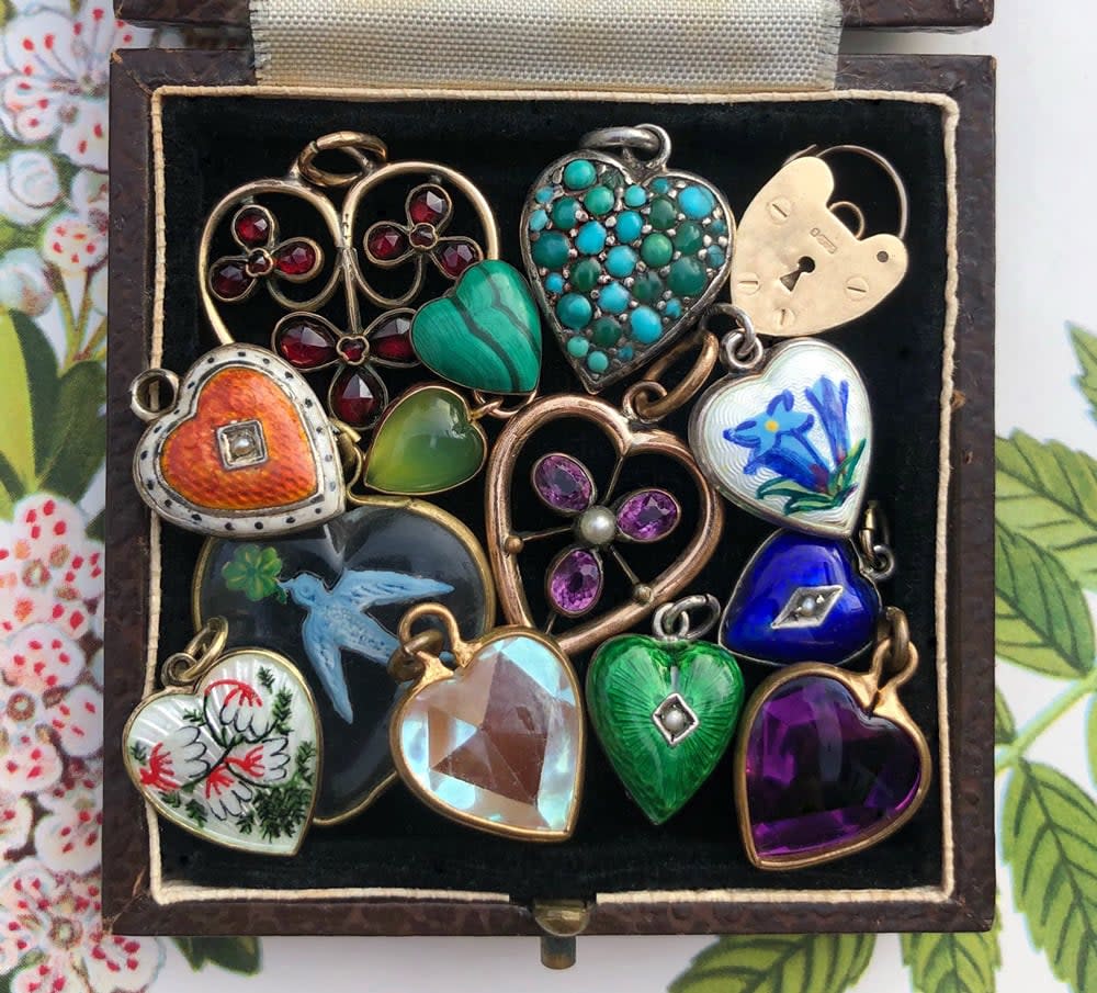 Various heart shaped pendants sit in a jewelry box. 