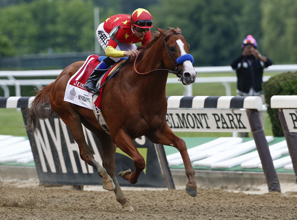 FILE - In this June 9, 2018, file photo, Justify, jockey Mike Smith up, crosses the finish line to win the 150th running of the Belmont Stakes horse race and the Triple Crown at Belmont Park in Elmont, N.Y. The Belmont Stakes will be run June 20, 2020, without fans and serve as the opening leg of horse racing's Triple Crown for the first time in the sport's history. The New York Racing Association on Tuesday, May 19, 2020, unveiled the rescheduled date for the Belmont, which will also be contested at a shorter distance than usual. This is the first time the Belmont will lead off the Triple Crown ahead of the Kentucky Derby and Preakness.(AP Photo/Peter Morgan, File)