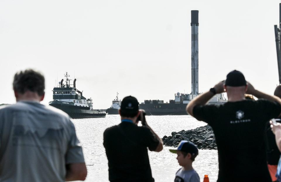 Spectators watch as a SpaceX first-stage booster returns to Port Canaveral aboard Just Read the Instructions on July 4, 2020.