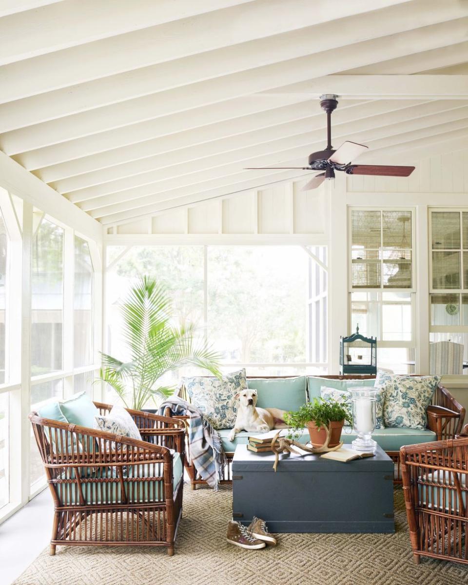 a screened porch with a fan with rattan furniture