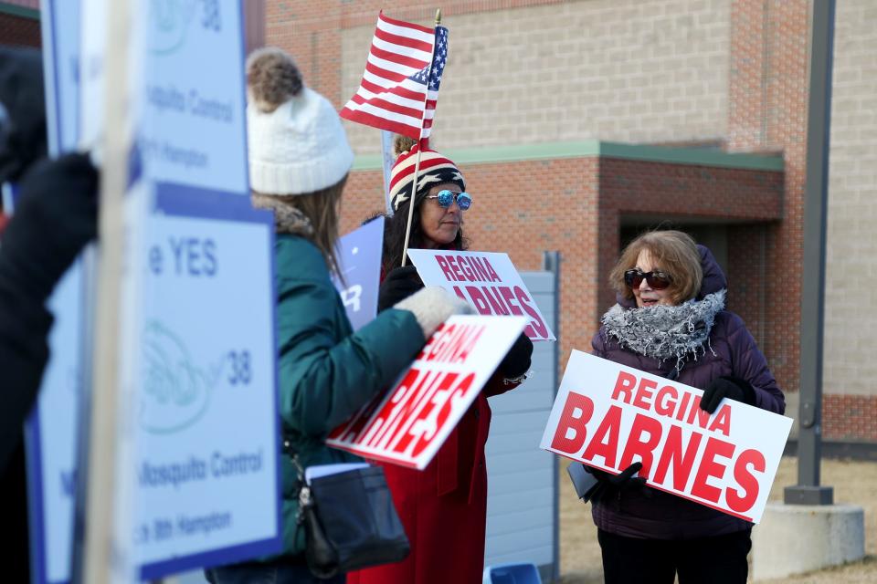 Hampton residents stand outside of Winnacunnet High School campaigning for candidates Tuesday, March 8, 2022.