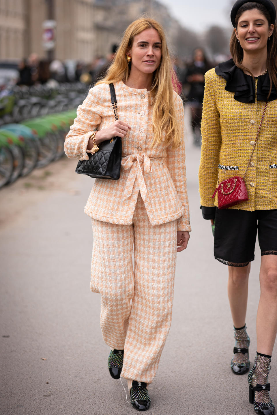 PARIS, FRANCE - MARCH 07: Blanca Miro (L) wears a peach checked Chanel suit, black Chanel bag and black decorated Chanel shoes and Maria de la Orden (R) wears a yellow Chanel  jacket, black shorts, Chanel heels and red Chanel bag, outside Chanel, during Paris Fashion Week - Womenswear Fall Winter 2023 2024, on March 07, 2023 in Paris, France. (Photo by Claudio Lavenia/Getty Images)