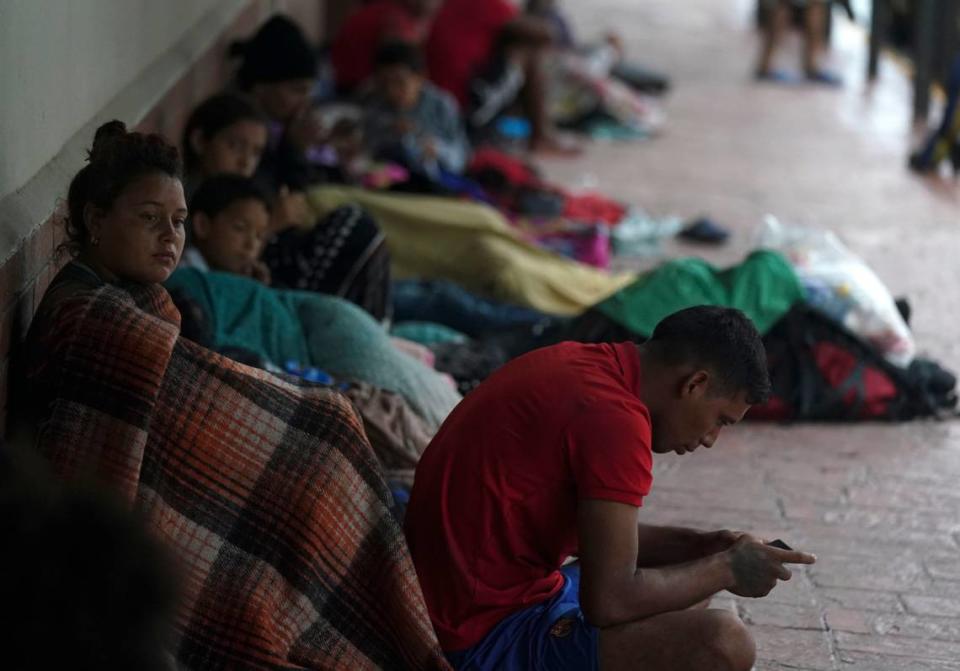 Migrantes venezolanos sentados junto al muro de un edificio mientras se protegen de la lluvia, cerca de las orillas del Río Grande en Matamoros, México, el sábado 13 de mayo de 2023.