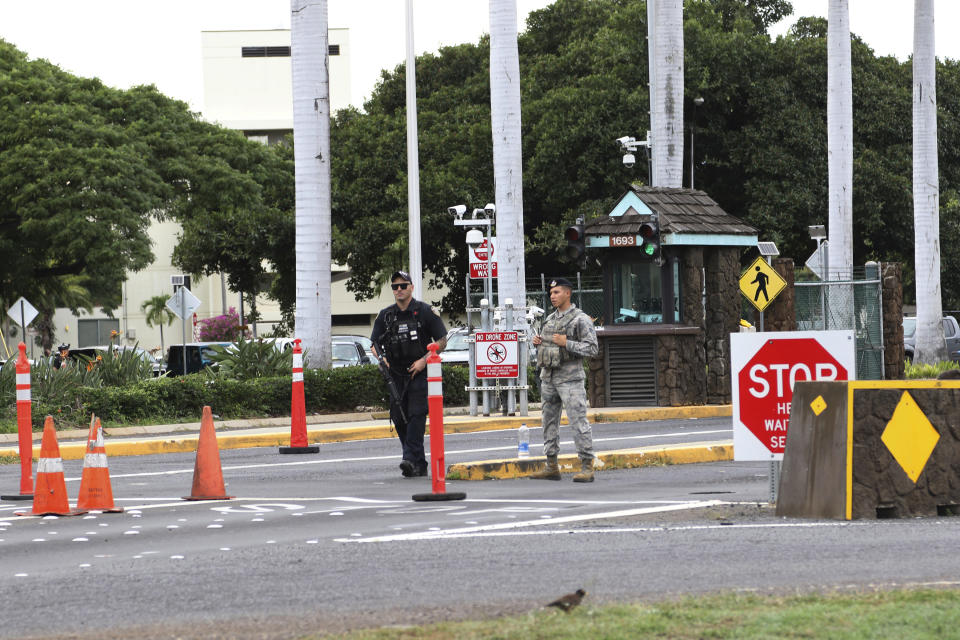 Security stand outside the main gate at Joint Base Pearl Harbor-Hickam, Wednesday, Dec. 4, 2019, in Hawaii. A shooting at Pearl Harbor naval shipyard in Hawaii left at least one person injured Wednesday, military and hospital officials said. (AP Photo/Caleb Jones)