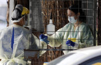 Medical staff prepare to take a COVID-19 tests at a drive through community based assessment centre in Christchurch, New Zealand, Thursday, Aug. 13, 2020. Health authorities in New Zealand are scrambling to trace the source of a new outbreak of the coronavirus as the nation's largest city, Auckland, goes back into lockdown. (AP Photo/Mark Baker)