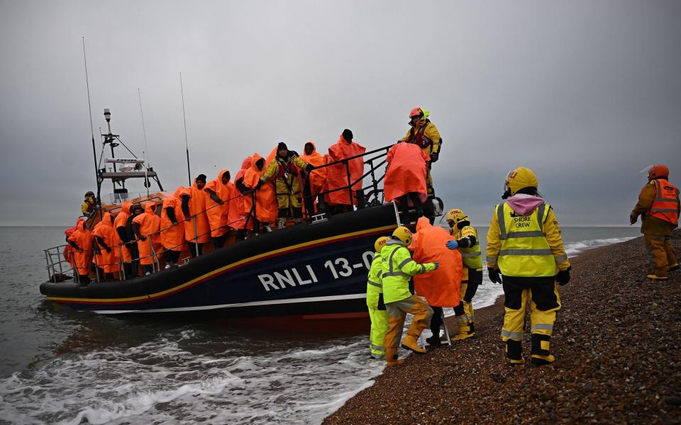 Migrants who were picked up at sea after attempting to cross the English Channel, are helped ashore in England - Ben Stansall / AFP