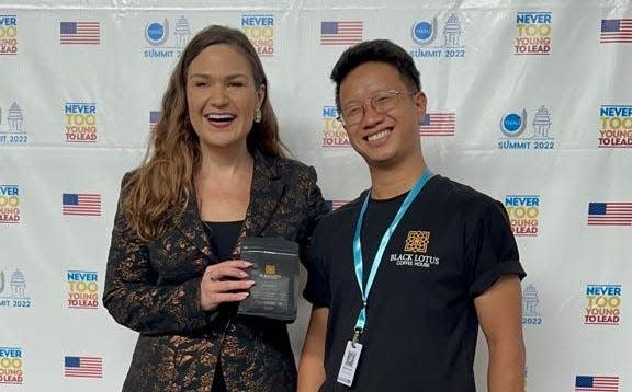 Abby Finkenauer, special envoy for the State Department's Global Youth Issues Office poses with Young Southeast Asian Leaders Initiative participant Hieu Nguyen and holds coffee from his start-up coffee business in Vietnam.