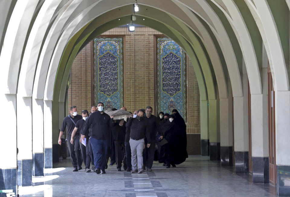 Mourners carry the body of a person who died from COVID-19 for burial, at the Behesht-e-Zahra cemetery just outside Tehran, Iran, Wednesday, April 21, 2021. After facing criticism for downplaying the virus last year, authorities have put partial lockdowns and other measures in place to try and slow the coronavirus’ spread, as Iran faces what looks like its worst wave of the coronavirus pandemic yet. (AP Photo/Ebrahim Noroozi)