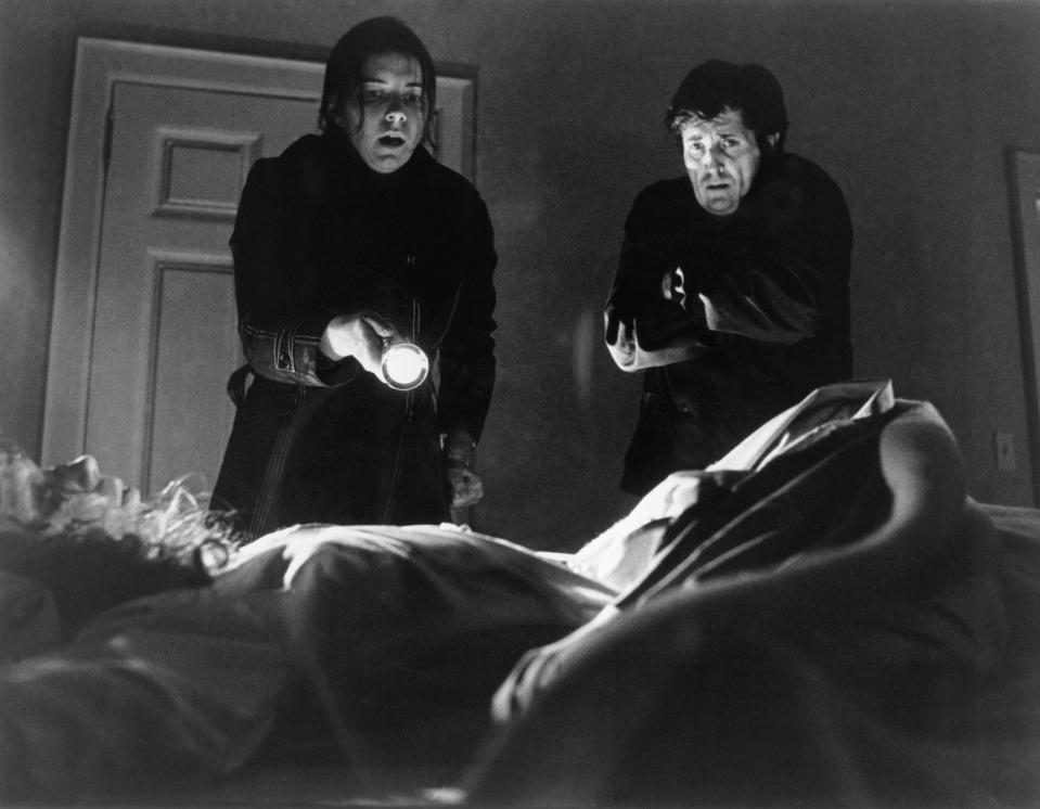 (Original Caption) 1973- Kitty Winn holds a flashlight at Linda Blair, in bed, as Jason Miller watches in this scene from "The Exorcist."