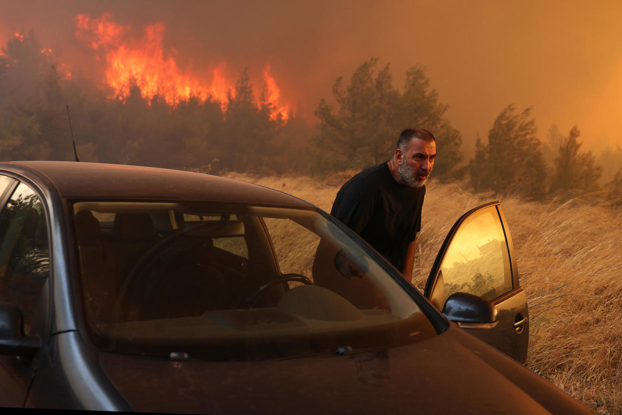 A man evacuates his house during a wildfire in Dione near Athens, Greece, on August 12, 2024. / Credit: Costas Baltas/Anadolu via Getty Images