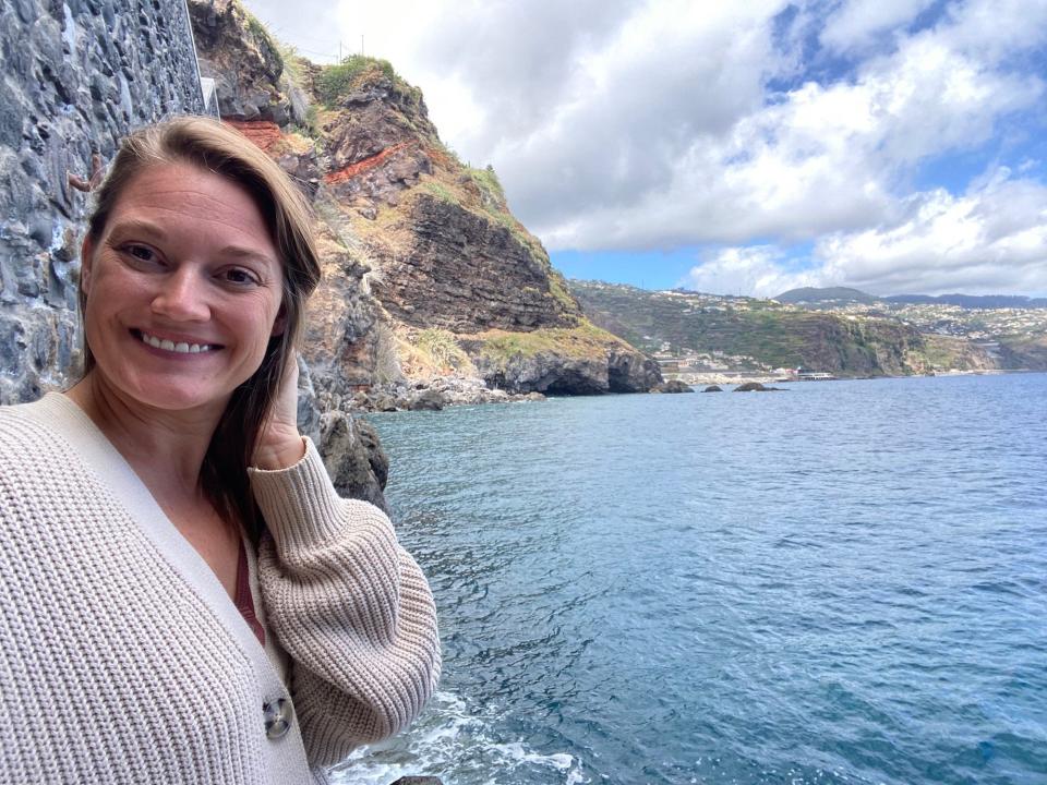 A woman smiles in a selfie in front of the sea.