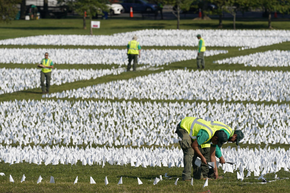 Workers plant white flags as part of artist Suzanne Brennan Firstenberg's temporary art installation, "In America: Remember," in remembrance of Americans who have died of COVID-19, on the National Mall in Washington, Wednesday, Sept. 15, 2021. The installation will consist of more than 630,000 flags when completed. (AP Photo/Patrick Semansky)