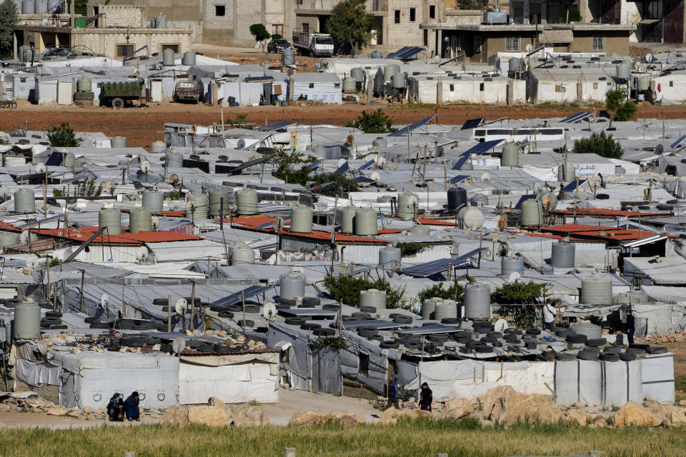 Syrian refugees sit outside their tents near the gathering point where other refugees prepare to back home to Syria as a part of a voluntary return, in the eastern Lebanese border town of Arsal, Tuesday, May 14, 2024. Hundreds of Syrians refugees left a remote northeastern Lebanese town back to Syria in a convoy, amid a surge in anti-refugee sentiment in the small, crisis-hit country. Lebanese officials for years has urged the international community to resettle the refugees in other countries or help them return to Syria. (AP Photo/Hussein Malla)