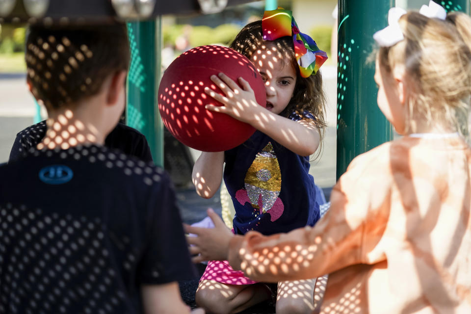 Scarlett Rasmussen, 8, tosses a ball with other classmates underneath a play structure during recess at Parkside Elementary School Wednesday, May 17, 2023, in Grants Pass, Ore. Chelsea Rasmussen has fought for more than a year for her daughter, Scarlett, to attend full days at Parkside. (AP Photo/Lindsey Wasson)