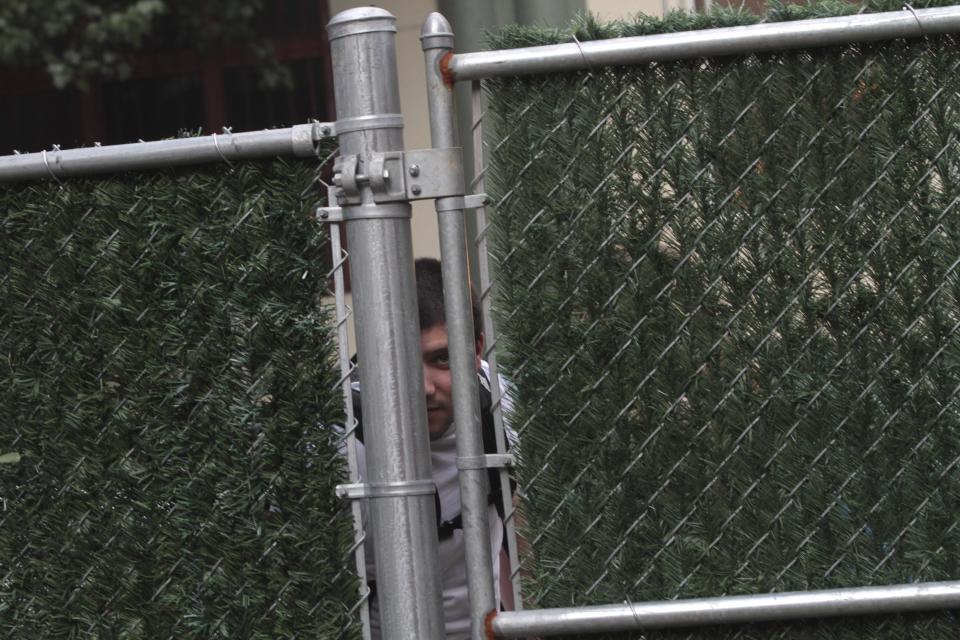 In this Wednesday, July 25 2012 photo, a man peaks through the fence at the activities inside Timeshare Backyard on the Lower East Side of Manhattan. The city's lone timeshare backyard allows New Yorkers to invite up to 30 guests for two hours at a time and comes with grills, lounge chairs and trashy magazines. (AP Photo/Mary Altaffer)