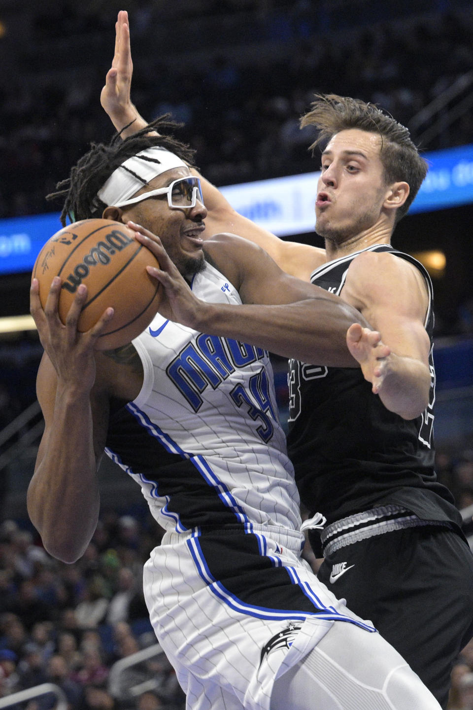 Orlando Magic center Wendell Carter Jr. (34) is fouled by San Antonio Spurs forward Zach Collins (23) while driving to the basket during the first half of an NBA basketball game Friday, Dec. 23, 2022, in Orlando, Fla. (AP Photo/Phelan M. Ebenhack)
