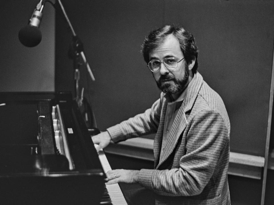 A photo of Bob James sitting at a piano and staring into the camera