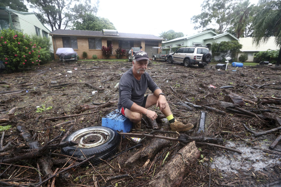 Shaun Ratko sits on debris and mud washed up onto his property in Port Macquarie, 400 kilometers (250 miles) north of Sydney, Tuesday, March 23, 2021. Some 18,000 residents of Australia's most populous state have fled their homes since last week, with warnings the flood cleanup could stretch into April. (Jason O'Brien/AAP Image via AP)