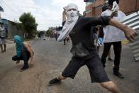 A masked demonstrator throws a rock at riot police during an anti-government protest in Valencia, Venezuela, Wednesday, Feb. 26, 2014. The protests began with students and were soon joined by others in several cities, upset over crime, economic problems and heavy-handed government response to the protests. (AP Photo/Rodrigo Abd)