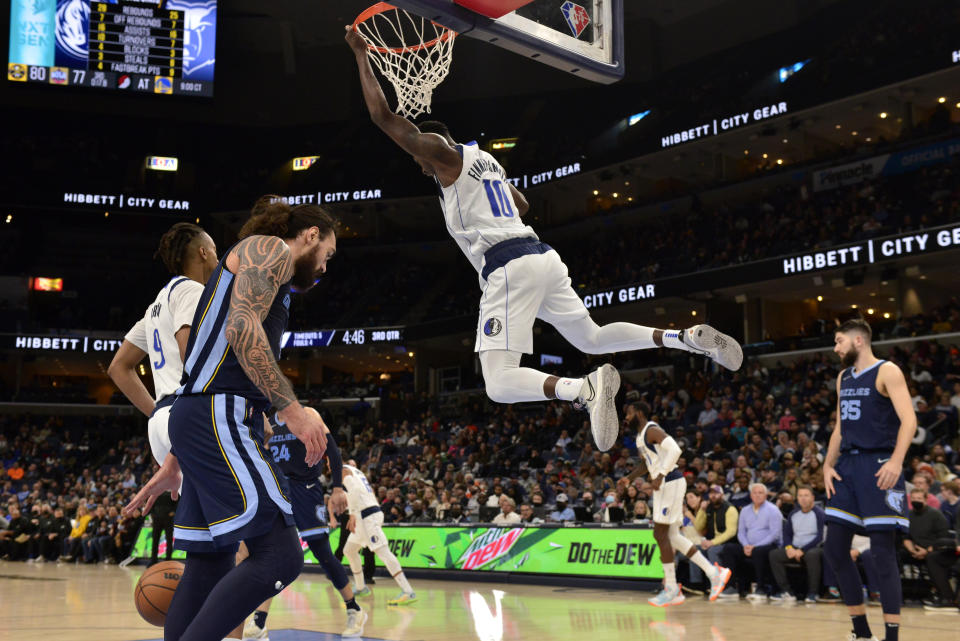 Dallas Mavericks forward Dorian Finney-Smith (10) hangs from the rim after a dunk during the second half of the team's NBA basketball game against the Memphis Grizzlies on Wednesday, Dec. 8, 2021, in Memphis, Tenn. (AP Photo/Brandon Dill)