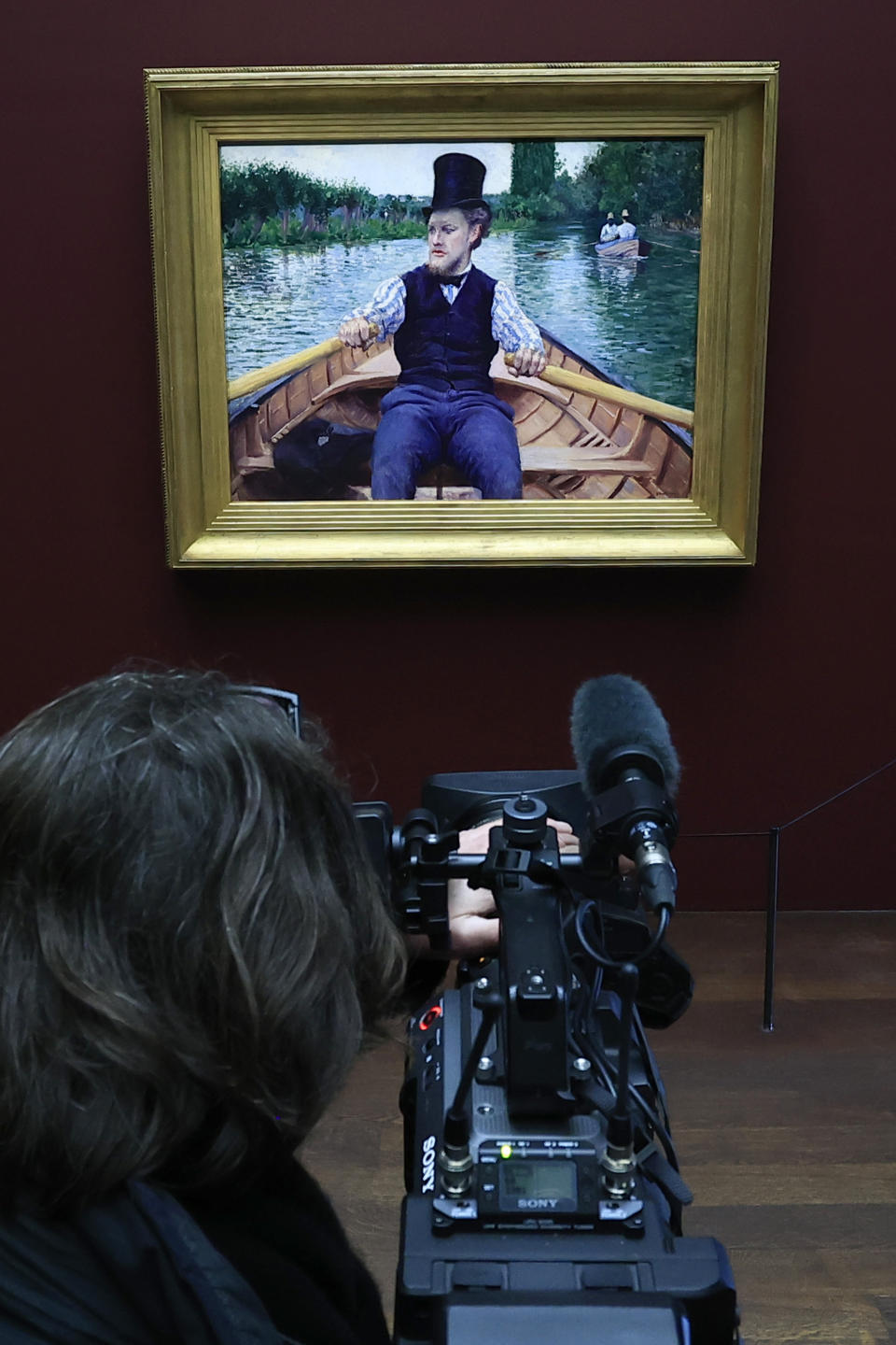 A video reporter films the painting "A Boating Party" by French painter Gustave Caillebotte at the Orsay Museum, Monday, Jan. 30, 2023 in Paris. France has acquired the stunning impressionist masterpiece for its national collection of art treasures, using a donation from French luxury goods giant LVMH to pay the 43-million euro ($47 million) price tag for Gustave Caillebotte's "A Boating Party." The work, remarkable in its realism, delicate coloring and almost cinematic perspective, as though the artist was in the boat with the rower, went on display in the Musée d'Orsay in Paris. (AP Photo/Aurelien Morissard)