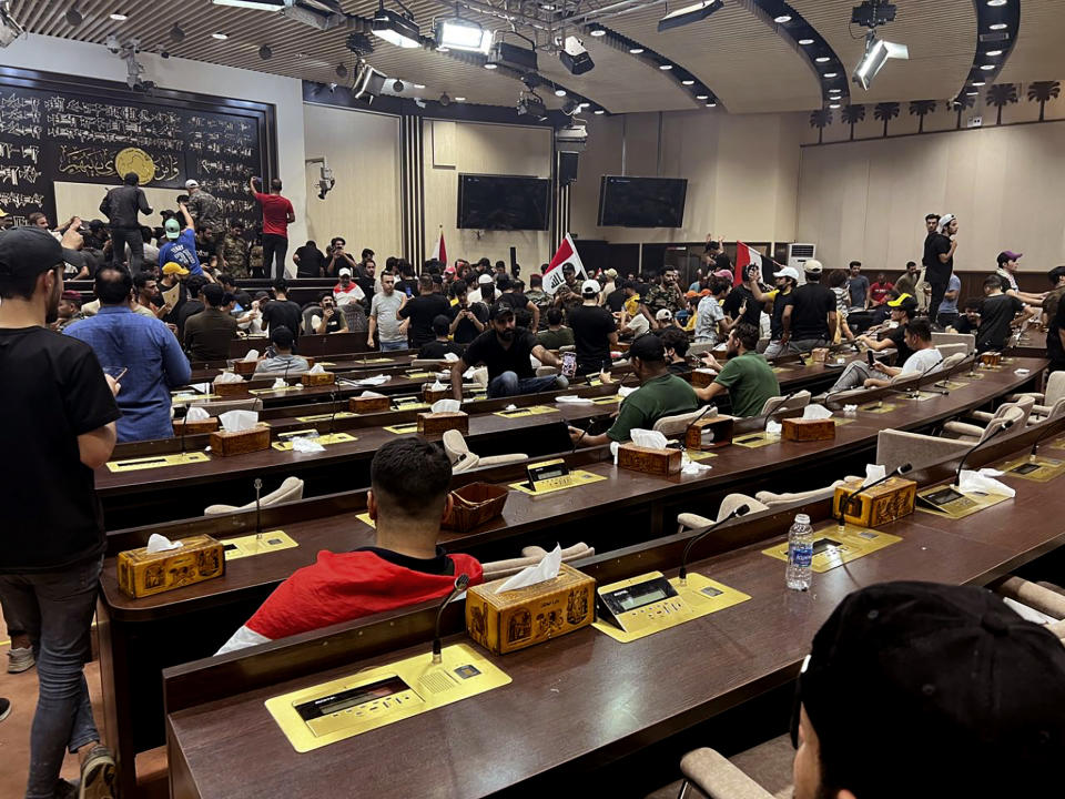 Hundreds of Iraqi protesters breached Baghdad's parliament in Baghdad, Iraq, Wednesday, July. 27, 2022. The majority of the protesters were followers of influential Shiite cleric Muqtada al-Sadr. The demonstrators, all of them men, were seen walking on tables of the parliament floor, sitting in the chairs of lawmakers and waving Iraqi flags. (AP Photo/Ali Abdul Hassan)