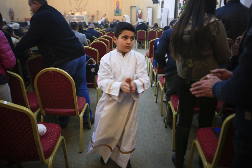 In this Jan. 20, 2019 photo, an altar boy shakes people’s hands during Sunday service at Mart Shmony Orthodox Church in Irbil, Iraq. Two years after it was liberated from Islamic State militants, only a fraction of Bartella’s Christian residents have returned. Most now live in Ankawa, the Christian neighborhood of Kurdish Irbil. (AP Photo/Fay Abuelgasim)