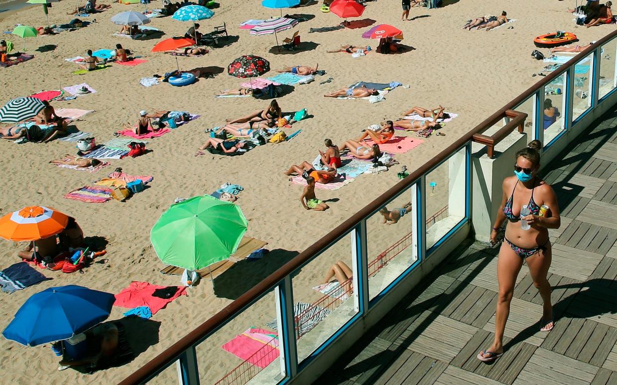 A woman walks, wearing a face mask to protect against coronavirus, near the beach, in Saint Jean de Luz, southwestern France - AP