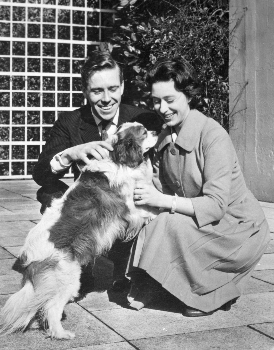 Princess Margaret and her fiance, photographer Antony Armstrong-Jones, play with one of her pet dogs at the Royal Lodge, Windsor. The princess and her fiance are pictured together for the first time since the announcement of their engagement. They are spending the weekend with the Queen Mother.