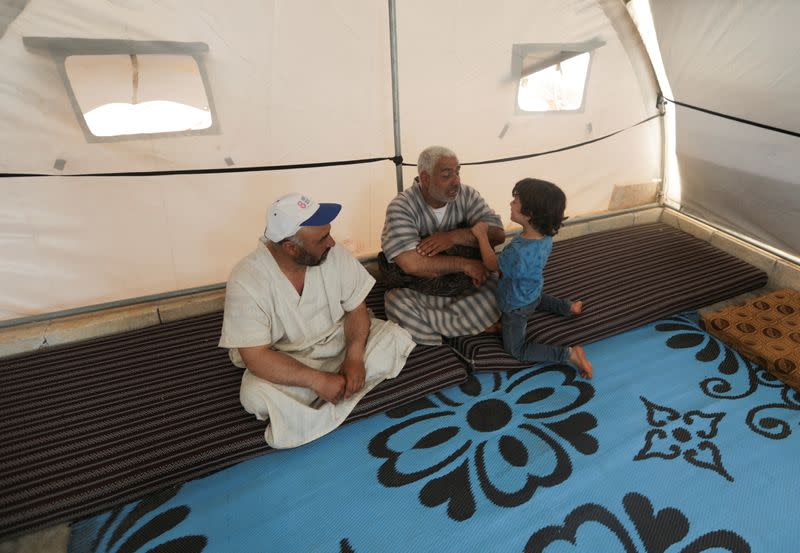 Youssef Ramadan, talks to his son as he sits inside a tent at Teh camp for internally displaced Syrians, in northern Idlib