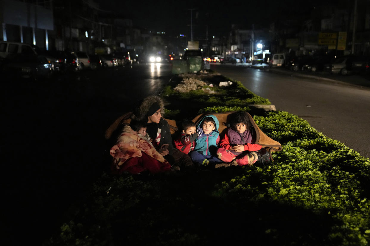 A family who fled the war in Syria and live in Beirut, sit outside their home following an earthquake that hit neighboring Turkey early Monday, Feb. 6, 2023, in south of Beirut, Lebanon. Many residents in Lebanon left their homes and took to the streets or drove in their cars away from buildings. A powerful earthquake hit southeast Turkey and Syria early Monday, toppling buildings and sending panicked residents pouring outside in a cold winter night. (AP Photo/Hussein Malla)