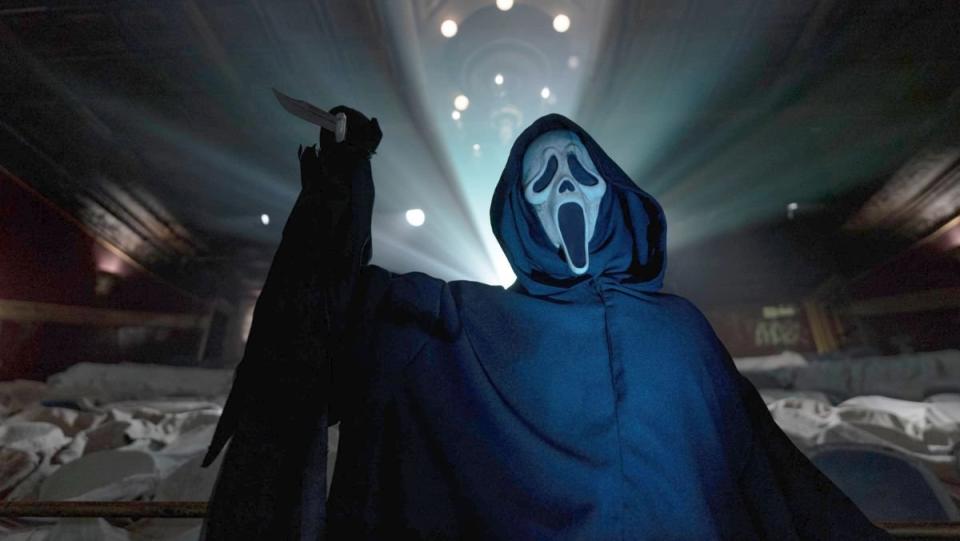 Ghostface stands in a lit theater holding a knife in Scream VI