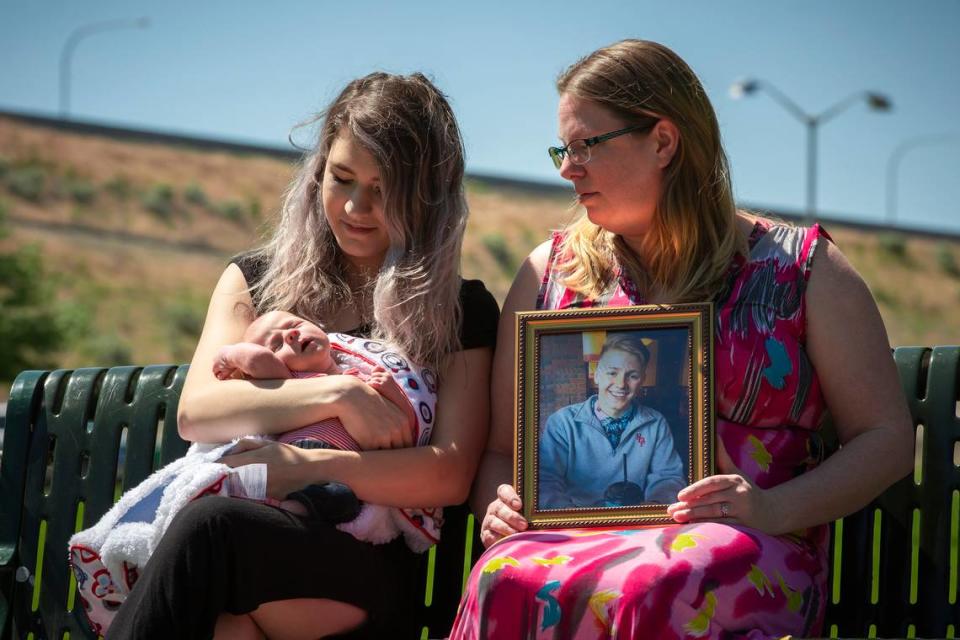 Cynarra Scott holds her son, Forrest, in 2019 with Dalyn Larsen, right, with a photo of her brother Hunter Black. Scott was pregnant when two masked men entered their home and shot her boyfriend, Hunter Black.