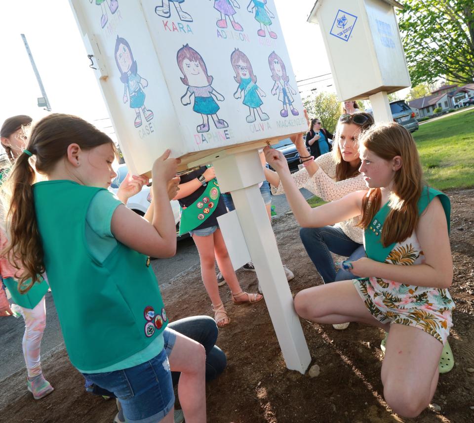 Raynham Junior Girl Scout Troop 82256 members, from left, Mackenzie MacEachern, Amber Fitch and troop leader Kathy McNeice work to attach the pantry box to its post to complete the new Little Free Pantry at Johnson's Pond in Raynham on Thursday, May 12, 2022. The Little Free Pantry is located right next to the local Cub Scout's Little Free Library.  