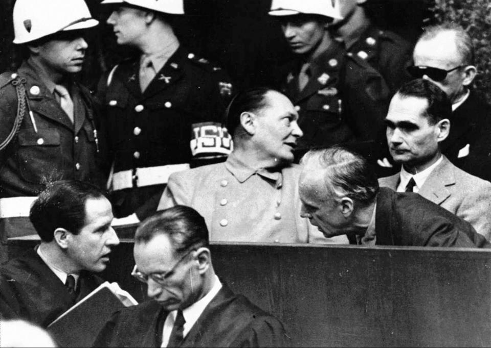 FILE - In this March 27, 1946 file photo, Nazi German Foreign Minister Joachim von Ribbentrop, right, leans in front of Rudolf Hess, Hitler's deputy, to confer with his lawyer, lower left, while Hermann Goering, center, chief of the German air force and one of Hitler's closest aides, turns to talks with Karl Doenitz, rear right, during the Nueremberg war crime trial session. Audio recordings from the historic Nuremberg trials will be made available to the public for the first time in digital form after a nearly two-year digitization process conducted in secret. The files capture around 1,200 hours of the high-profile trial of Nazi leaders in Nuremberg, Germany from 1945 to 1946. (AP Photo, File)