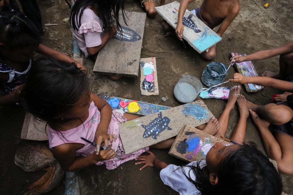 Children paint leatherback turtles on wood in Armila, Panama, Saturday, May 20, 2023. Sea turtles in Panama now have the legal right to live in an environment free of pollution and other detrimental impacts caused by humans, a change that represents a different way of thinking about how to protect wildlife. (AP Photo/Arnulfo Franco)