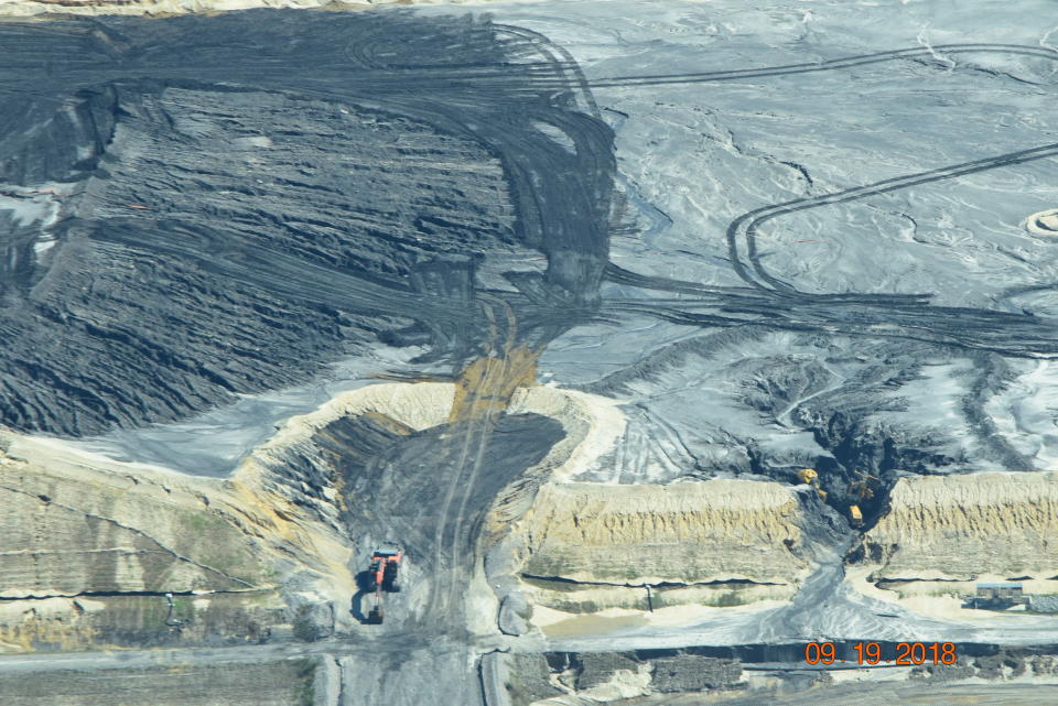 In this Sept. 19, 2018, photo released by Cape Fear River Watch, an earth mover is used to repair one of several breaches in a ruptured coal ash landfill at the L.V. Sutton Power Station in Wilmington, N.C. The landfill under construction at the site meant to hold coal ash in lined terraces ruptured over the weekend from heavy rains from Hurricane Florence, spilling enough material to fill 180 dump trucks. Coal ash contains arsenic, mercury and other toxic metals. (Kemp Burdette/Cape Fear River Watch via AP)