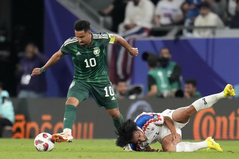 Saudi Arabia's Salem Aldawsari, left, controls the ball as Thailand's Supachok Sarachat falls down during the Asian Cup Group F soccer match between Saudi Arabia and Thailand at Education City Stadium, in Al Rayyan, Qatar, Thursday, Jan. 25, 2024. (AP Photo/Aijaz Rahi)