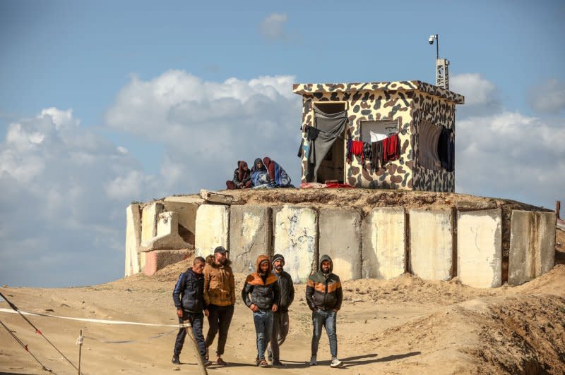 Women sit by clothes drying on a laundry line outside a Palestinian outpost painted in camouflage colours near a tent camp sheltering refugees who have fled fighting between Israeli and Palestinian forces in Rafah in the southern Gaza Strip on Thursday. Photo by Ismael Mohamad/UPI