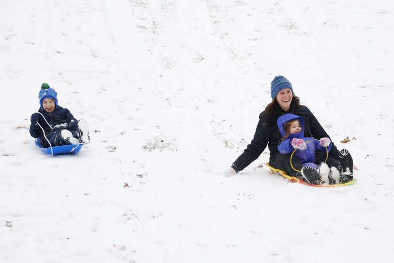 Children sled in Central Park as snow falls accompanied by cold temperatures in New York City on Tuesday. Photo by John Angelillo/UPI