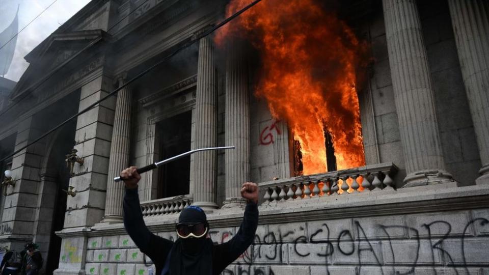 Un manifestante encapuchado frente a las oficinas del Congreso incendiadas.