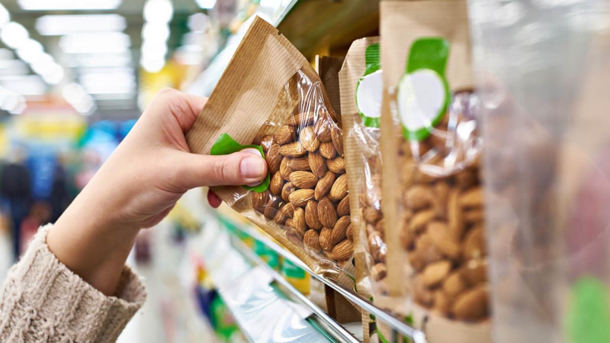 Hand of the buyer with the packaging of almond nuts in the store.