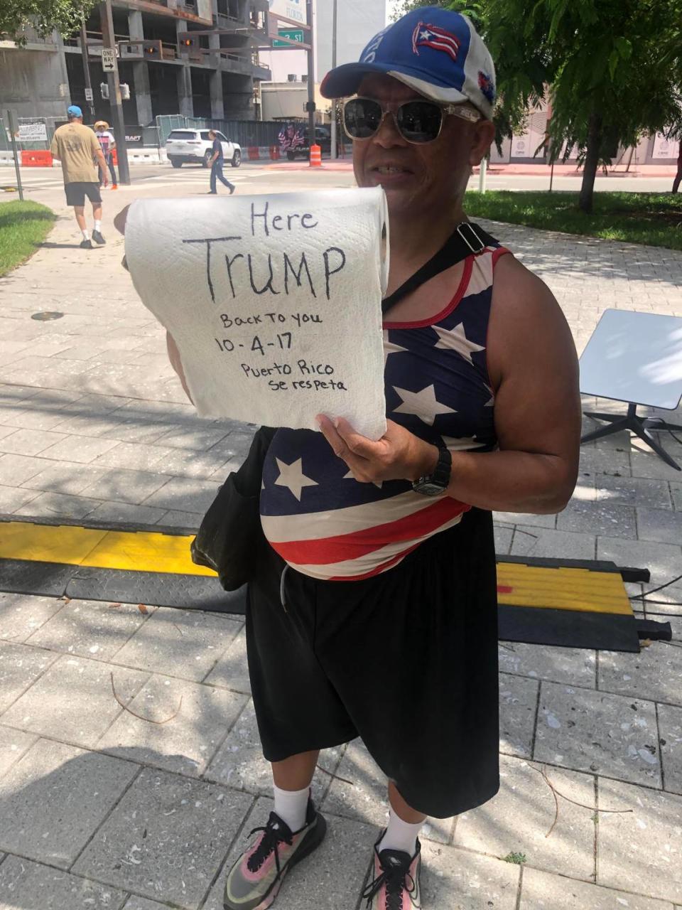 Remigio Echevarria, a 52-year-old handyman from Añasco, Puerto Rico, hands paper towels outside the federal courthouse, a nod to the time President Trump famously tossed rolls to a crowd in San Juan in October 2017 after Hurricane Maria devastated the island. One towel reads, “Here Trump, back to you. Puerto Rico respects itself.”
