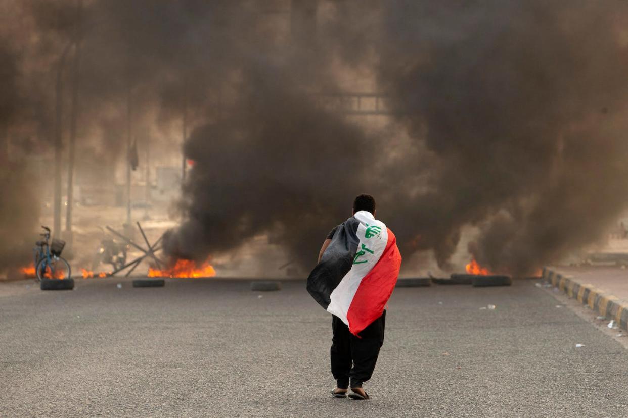 An Iraqi person walks down a road blocked by burning tires in Basra in August 2002. <a href="https://media.gettyimages.com/id/1242803428/photo/topshot-iraq-politics-sadr-demo.jpg?s=1024x1024&w=gi&k=20&c=S4tOIc6I7PC-scxNWjeb_aZUVwt5U2jKeyr1k5lyhzo=" rel="nofollow noopener" target="_blank" data-ylk="slk:Hussein Faleh/AFP via Getty Images;elm:context_link;itc:0;sec:content-canvas" class="link ">Hussein Faleh/AFP via Getty Images</a>