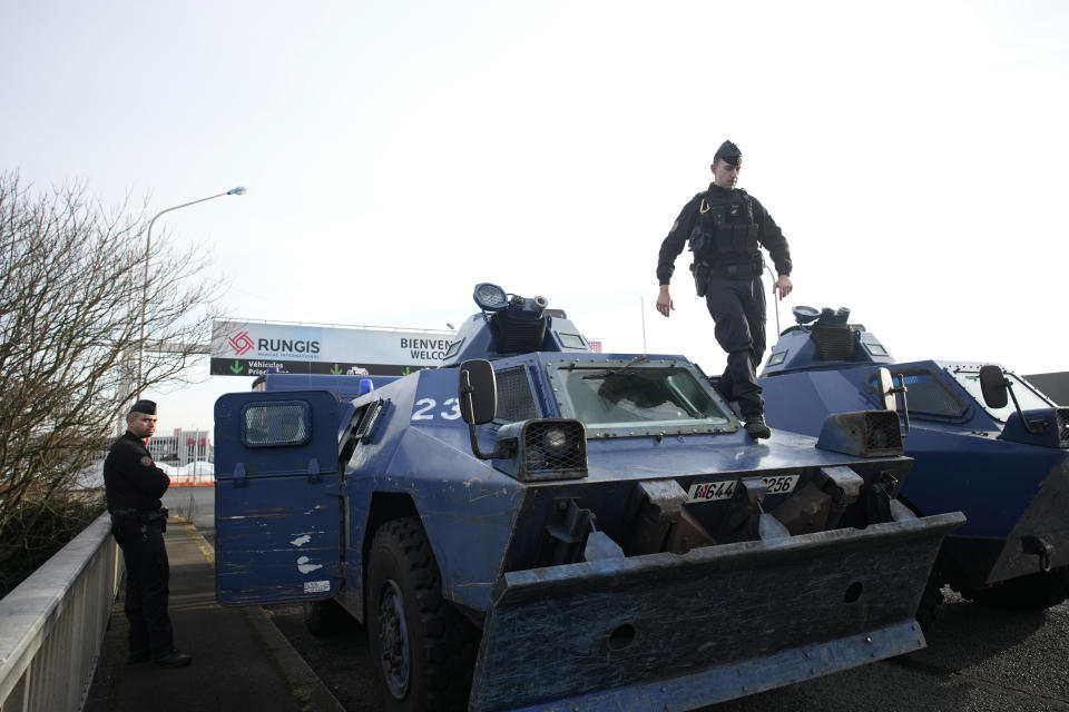 A gendarme walks atop a military vehicle at the entrance of the Rungis International Market, which supplies the capital and surrounding region with much of its fresh food, Monday, Jan. 29, 2024 south of Paris. Protesting farmers intended to encircle Paris with barricades of tractors, aiming to lay siege to France's seat of power in a battle with the government over the future of their industry shaken by the repercussions of the Ukraine war. (AP Photo/Christophe Ena)