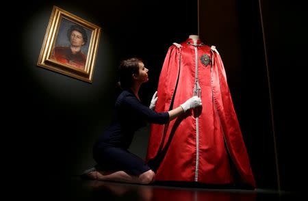 A member of the Royal Collection Trust, poses for photographers next to Britain's Queen Elizabeth's 'Mantle of The Order of The British Empire' robe, ahead of the opening of an exhibition entitled 'Fashioning a Reign: 90 Years of Style from the Queen's Wardrobe', at Buckingham Palace, in London, Britain July 21, 2016. REUTERS/Peter Nicholls