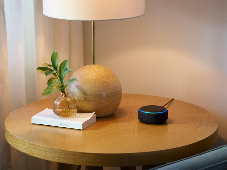 Amazon Echo Dot sitting on a table next to a lamp