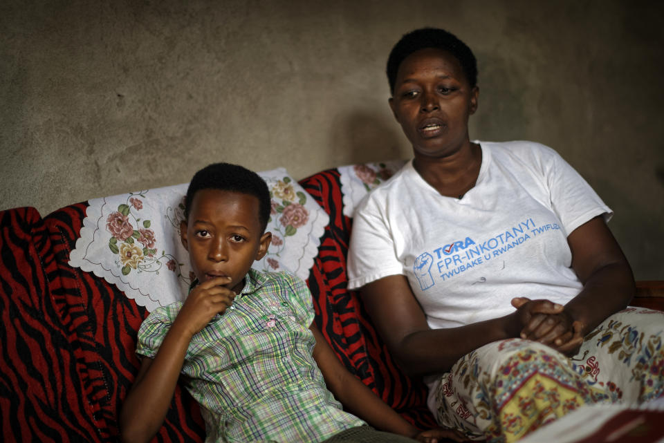 In this photo taken Thursday, April 4, 2019, genocide survivor Jannette Mukabyagaju, 42, recounts her experience as her 8-year-old daughter Natasha Umutesi listens, in their home in the reconciliation village of Mbyo, near Nyamata, in Rwanda. Twenty-five years after the genocide the country has six "reconciliation villages" where convicted perpetrators who have been released from prison after publicly apologizing for their crimes live side by side with genocide survivors who have professed forgiveness. (AP Photo/Ben Curtis)