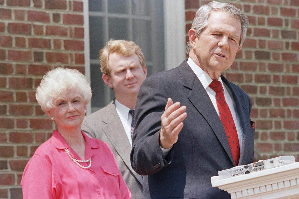 Pat Robertson, gestures as he announces that he is suspending his campaign during a press conference, at his home in Virginia Beach, Virginia. Listening to Robertson are his son Tim and wife Dede Pat Robertson and Dede Robertson, Virginia Beach