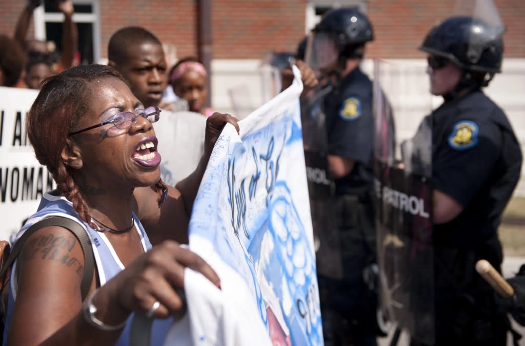 Marcelle Stewart, left, confronts police officers during a march and rally in downtown Ferguson, Mo., Monday, Aug. 11, 2014. (AP Photo/Sid Hastings, File)